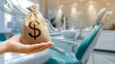 Hand holding money bag in front of teal dental chair