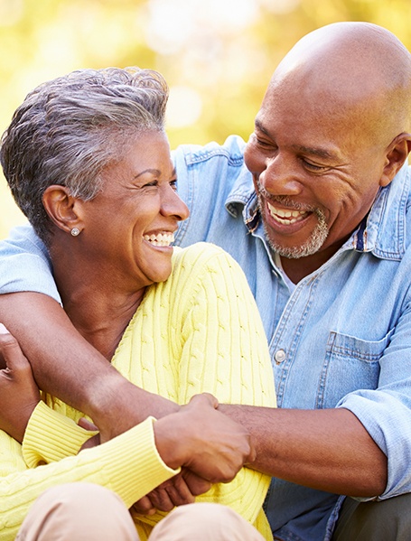 Man in blue shirt hugging woman in yellow sweater outisde