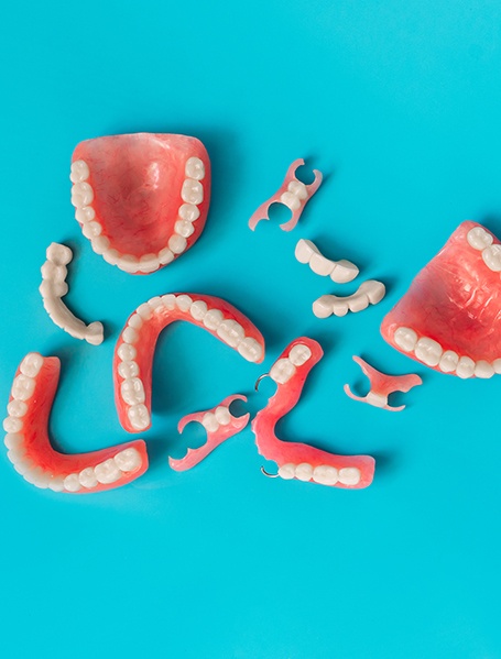 Bird’s eye view of several sets of dentures on a light blue surface