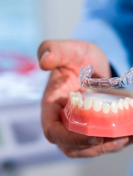 Dentist placing clear aligner on model of teeth