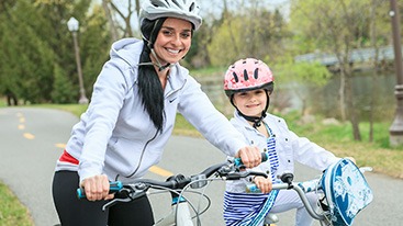 Mother and daughter smiling while riding bikes outside